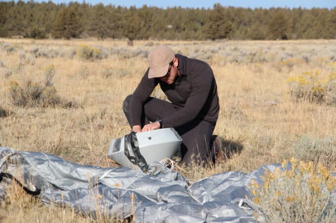 Engineer examines prototype RED payload return capsule after precision landing test